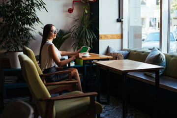 businesswoman sits at a table in an office and looks at a tablet pc. mosk up