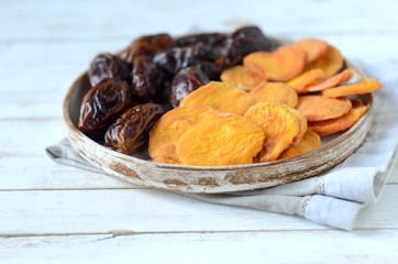 Dried dates and dried apricots on a white wooden background