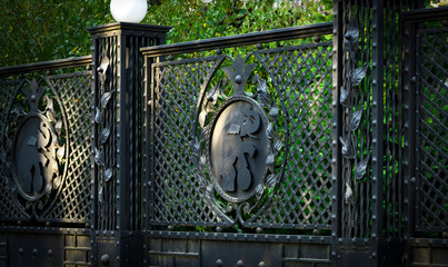 Part of the iron-gates curtained against the background of green trees.