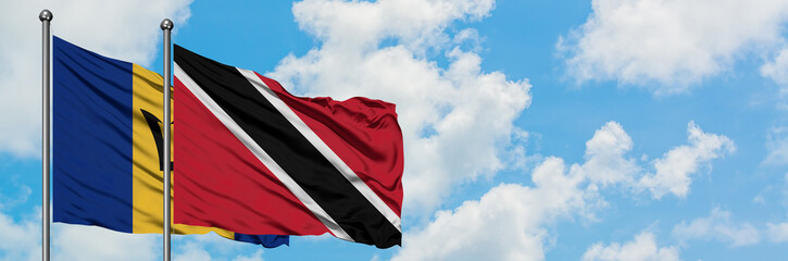 Barbados and Trinidad And Tobago flag waving in the wind against white cloudy blue sky together. Diplomacy concept, international relations.