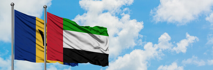 Barbados and United Arab Emirates flag waving in the wind against white cloudy blue sky together. Diplomacy concept, international relations.