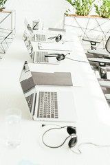 selective focus of laptops near headsets on table in office