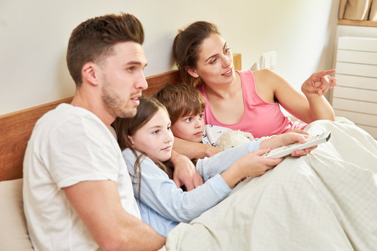Eltern und Kinder schauen Fernsehen im Bett