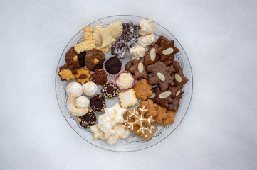 Many kinds of Christmas cookies on two cut glass transparent plates in white snow