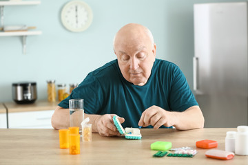 Elderly man with different pills at home