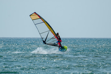 Young girl learns to control a board with a sail