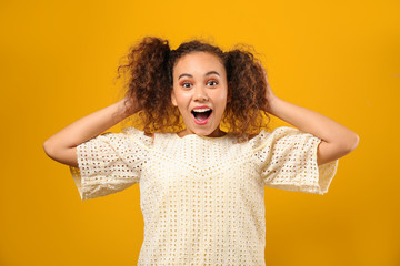 Portrait of surprised African-American woman on color background