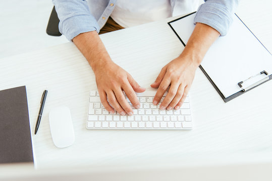 top view of broker typing on computer keyboard in office