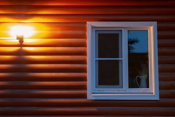 Obraz na płótnie Canvas Lantern on the wall of a wooden house. The window is in the foreground...