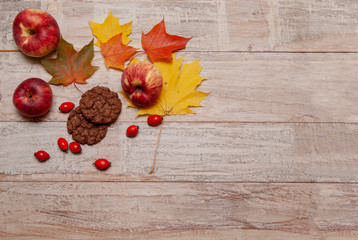 Naklejka na ściany i meble Autumn composition of maple leaves, apples and cookies on a texture board