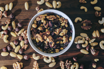 top view of a white bowl with mixed nuts on a wood