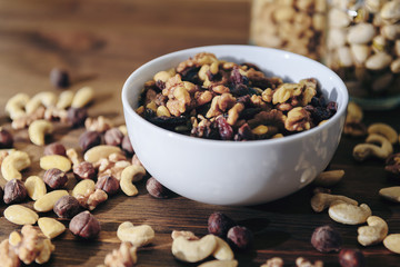 white bowl with organic mixed nuts on wooden table
