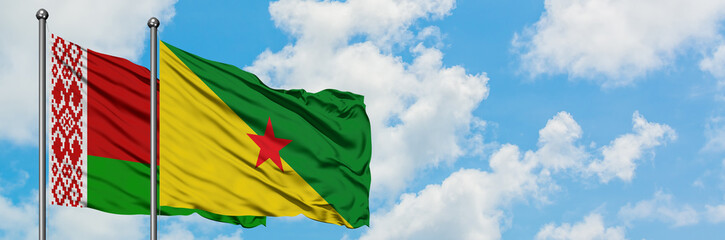 Belarus and French Guiana flag waving in the wind against white cloudy blue sky together. Diplomacy concept, international relations.