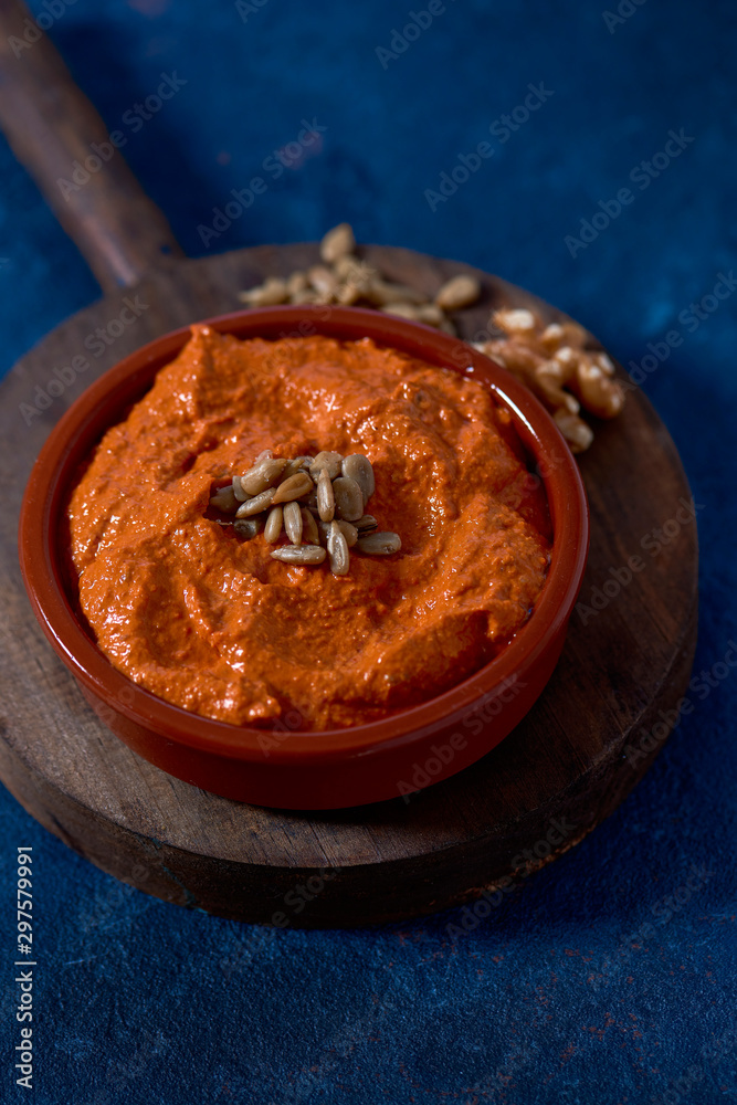 Poster homemade muhammara in a brown earthenware bowl.