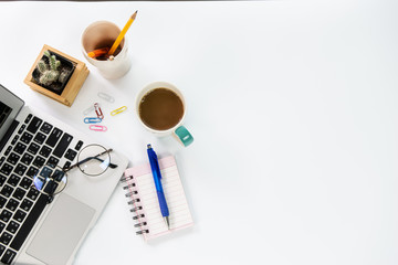 top view of office desk workspace with coffee cup, notebook, smartphone and keyboard on white background with copy space,