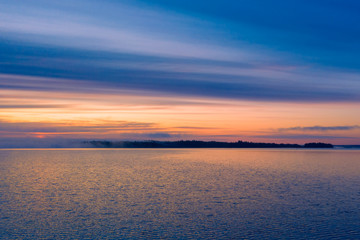 Long Exposure of Sunset at the Paijanne lake. Beautiful scape with sunrise sky, pine forest and water. Lake Paijanne, Finland.