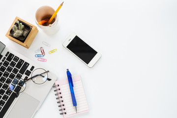 top view of office desk workspace with coffee cup, notebook, smartphone and keyboard on white background with copy space,