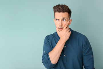 Obraz premium Thoughtful young man on color background