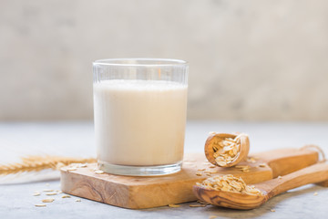 The concept of a vegetarian diet. Oat milk in the glass with jug of milk and oat.  Light background