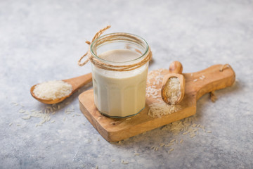 The concept of a vegetarian diet. Rice milk in the glass with rice grains . Light background