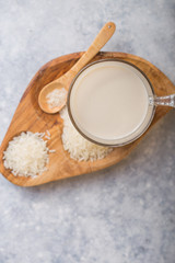 The concept of a vegetarian diet. Rice milk in the glass with rice grains . Light background