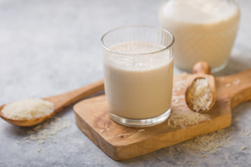 The concept of a vegetarian diet. Rice milk in the glass with rice grains . Light background