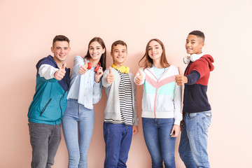 Obraz premium Portrait of teenagers showing thumb-up on color background