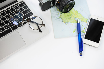 Desk with a notebook, telephone, camera, map, and planning a trip on white background with copy space