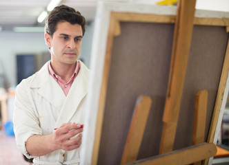 Man near easel painting on canvas