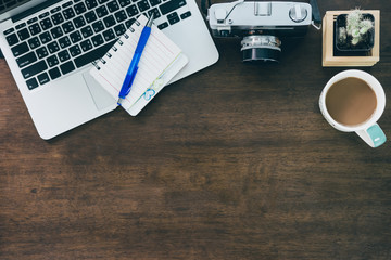 top view of office desk workspace with coffee cup, notebook, smartphone and keyboard on wood background with copy space,