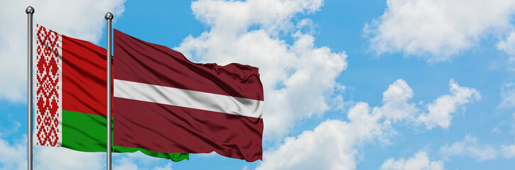 Belarus and Latvia flag waving in the wind against white cloudy blue sky together. Diplomacy concept, international relations.