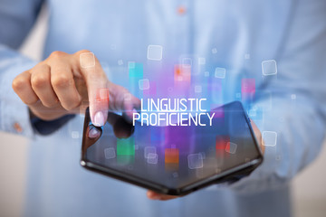 Young man holding a foldable smartphone with LINGUISTIC PROFICIENCY inscription, educational concept