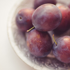 Ripe purple plums in a silver plate closeup.