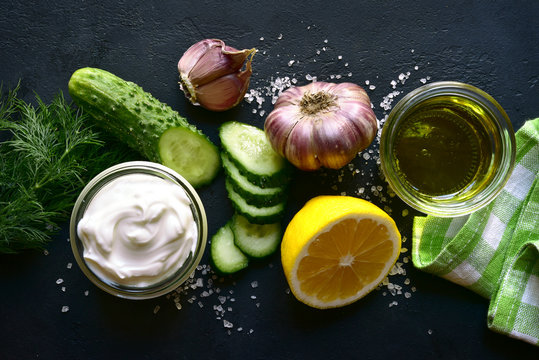 Ingredients for making traditional greek sauce tzatziki : yogurt, olive oil, fresh cucumber, garlic and dill. Top view with copy space.