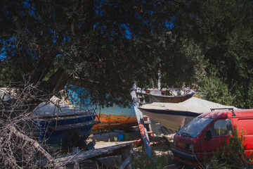 Fototapeta na wymiar Abandoned boats and van under the trees