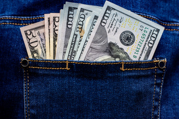 Different american dollar bills in blue jeans pocket.