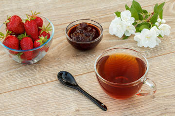 Glass cup of tea, strawberries with white jasmine flowers