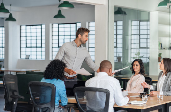 Businessman Handing Out Paperwork During An Office Meeting