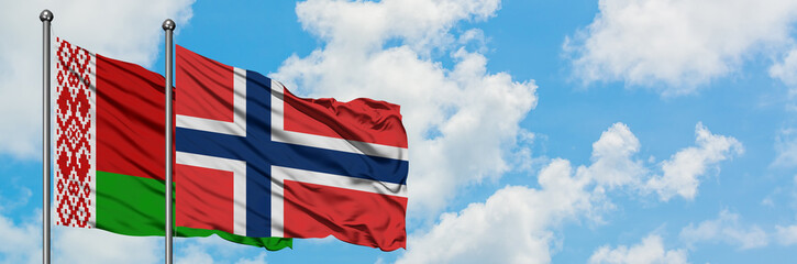 Belarus and Norway flag waving in the wind against white cloudy blue sky together. Diplomacy concept, international relations.