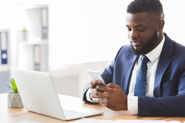 Handsome businessman using cellphone at workplace, sending email