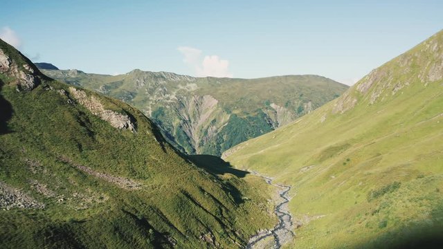 AERIAL ,4K; drone view of natural landscape with mountain riges, alpine steep slopes and valleys; early morning time; rocky cliffs and glasiers; beautiful panorama of summits, river with melting ice