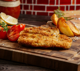 crispy fried chicken served with fried potatoes, fresh lemon and tomates