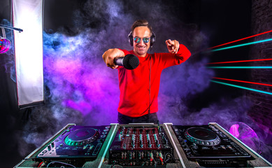 Attractive Dj with microphone  playing on the turntable at night club. Club, nightlife.