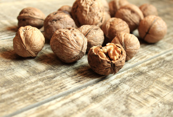 Walnuts lie on a wooden background. One nut is chopped.