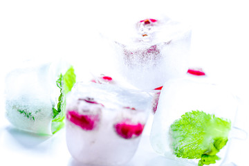 frozen red berries in ice cubes with mint on stone background