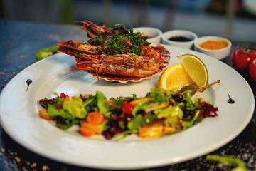 fried shrimps in garlic sauce served in shell, with fresh salad and lemon