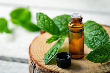 small glass bottle with mint essential oil on wooden background