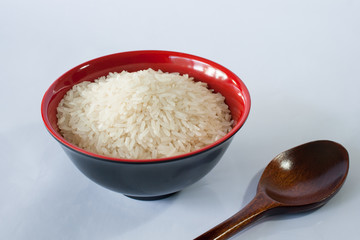 rice in a red bowl and spoon on white background