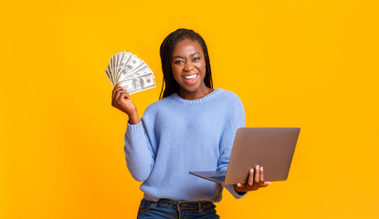 African american young woman making money from internet, using laptop - obrazy, fototapety, plakaty