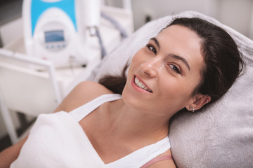 Close up of a happy beautiful woman with healthy smooth skin smiling to the camera, relaxing at beauty clinic. Skincare, health, body concept